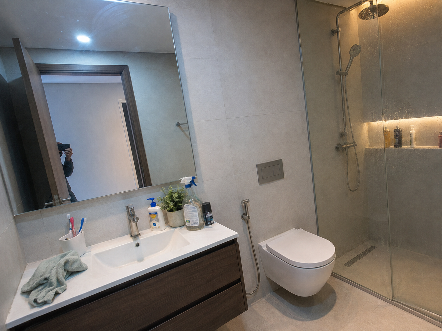 AI-generated bathroom with toiletries, water marks, mixed lighting and a photographer reflection